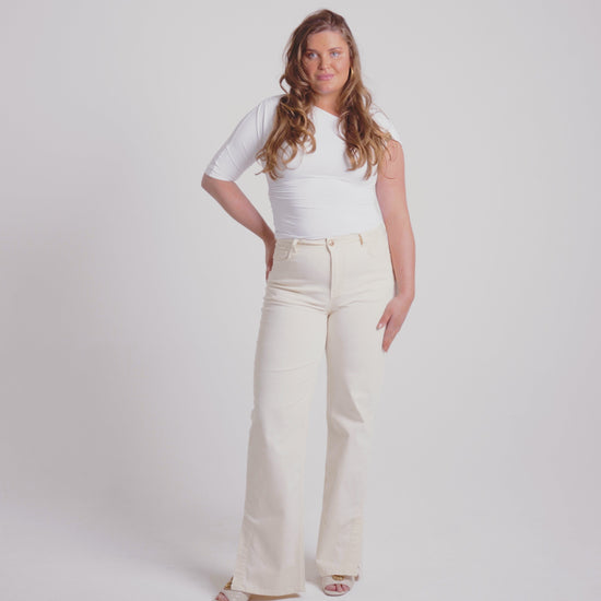 Woman with off white stretch jeans golden button